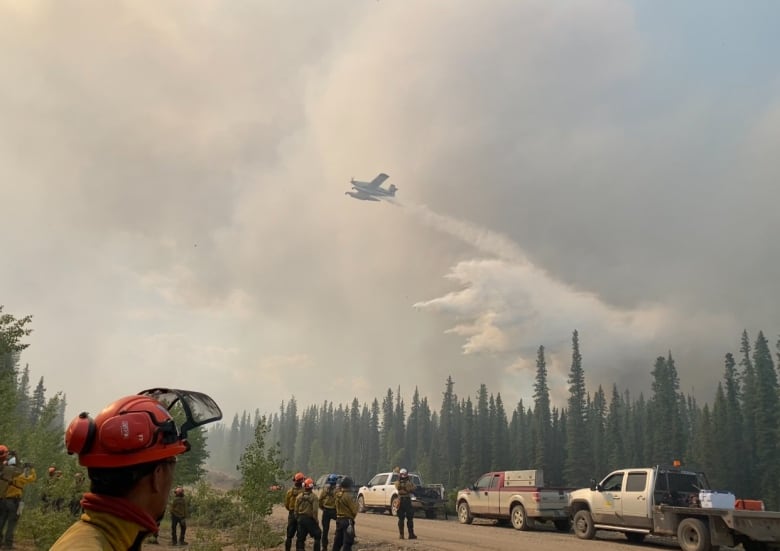 Firefighters look at smoke and water falling.