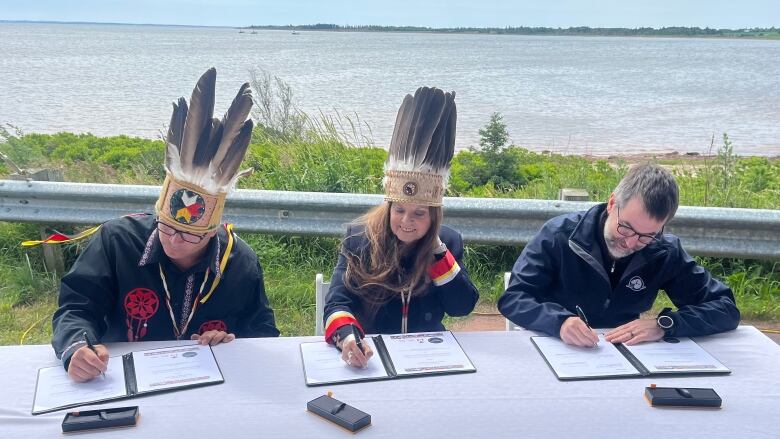 From left, Abegweit First Nation Chief Junior Gould, Lennox Island First Nation Chief Darlene Bernard and federal Environment Minister Steven Guilbeault, sign a co-governance agreement for Pituamkek, a National Park Reserve off P.E.I.'s North Shore.