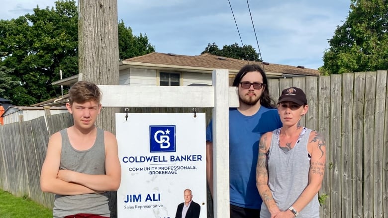 Family stands beside for sale sign