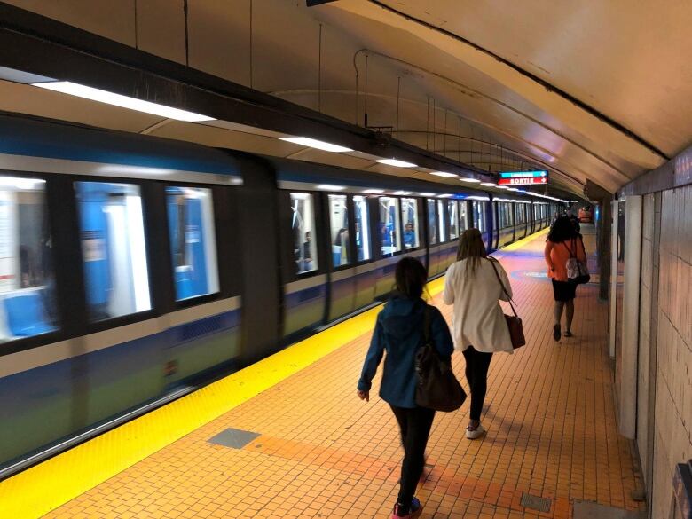 People walk on a subway platform.