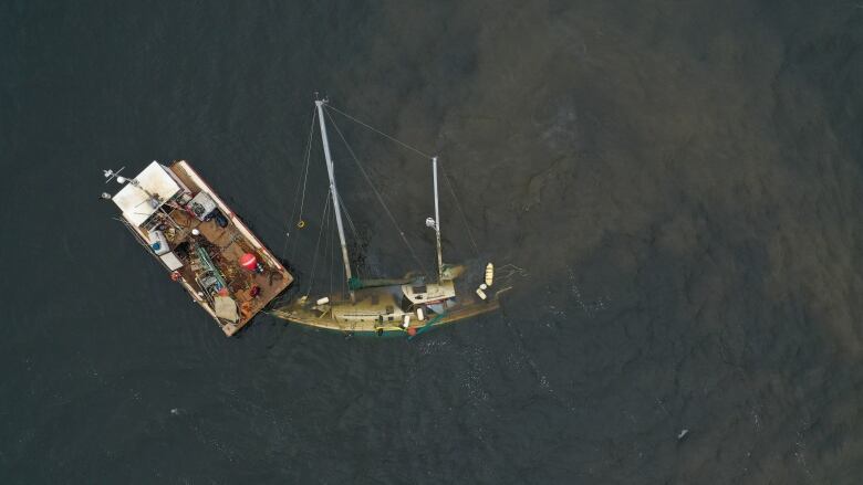 Aerial shot of a barge next to a sunken sailboat. 