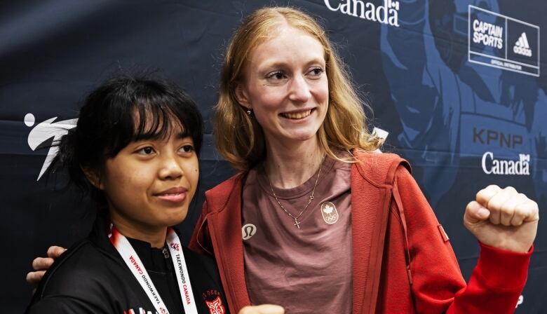 A woman holds her arm around a young girl as they smile to a camera.