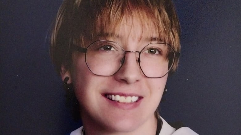 A student in grad robes smiles in a school photo.