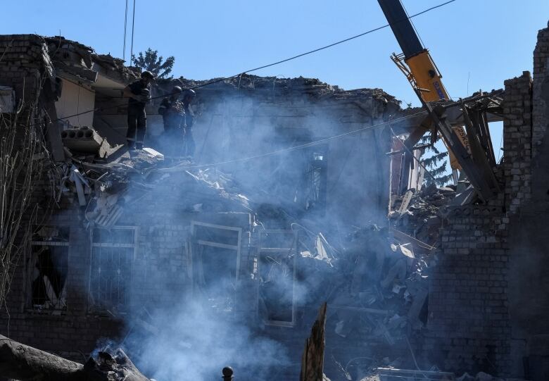 Smoke is seen as part of a building appears cratered and heavily damaged.