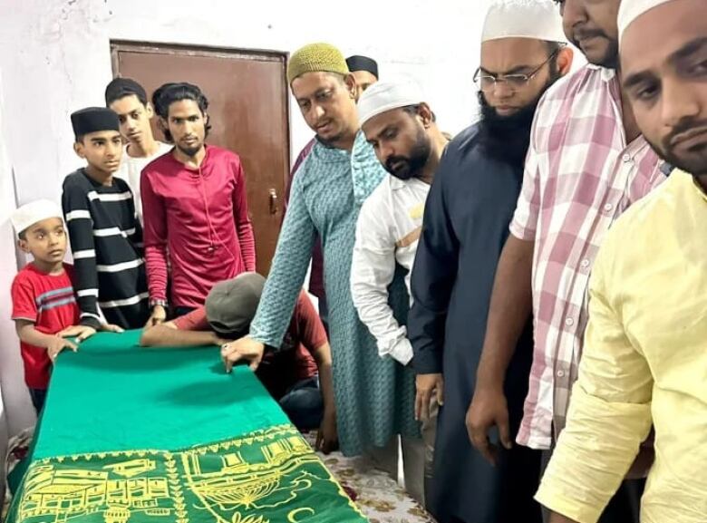 Men stand around a casket.