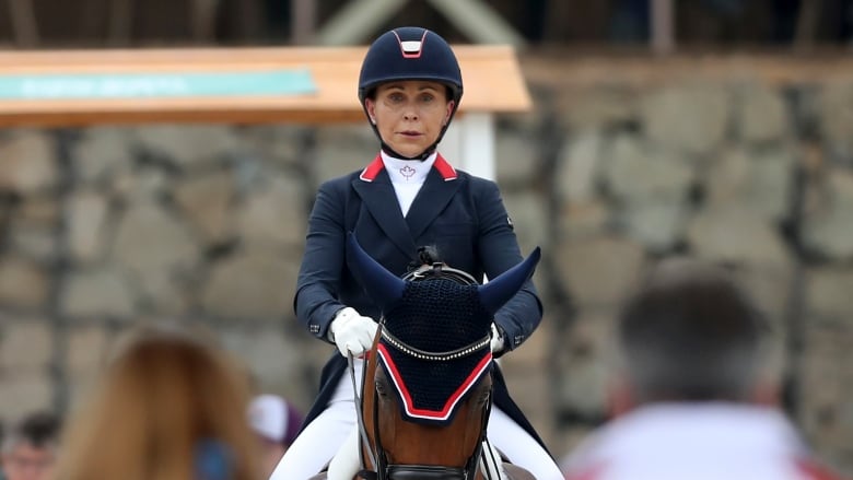 A woman in an equestrian outfit riding a horse