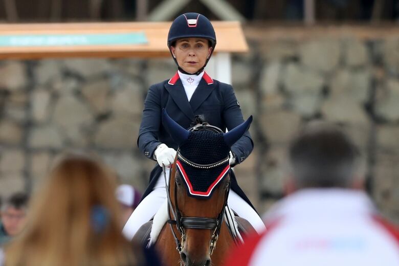 A woman in an equestrian outfit riding a horse