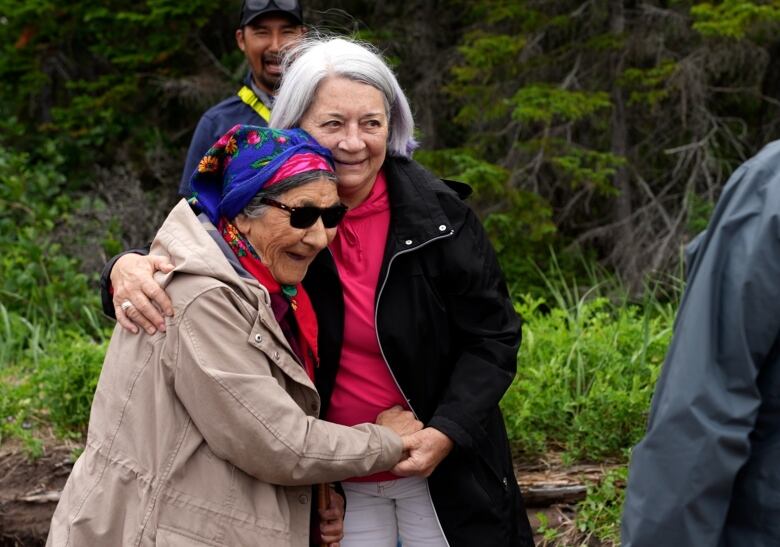 Two women embrace while laughing. 