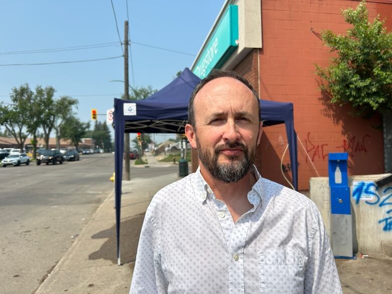 A man in a shirt standing in front of a misting station.