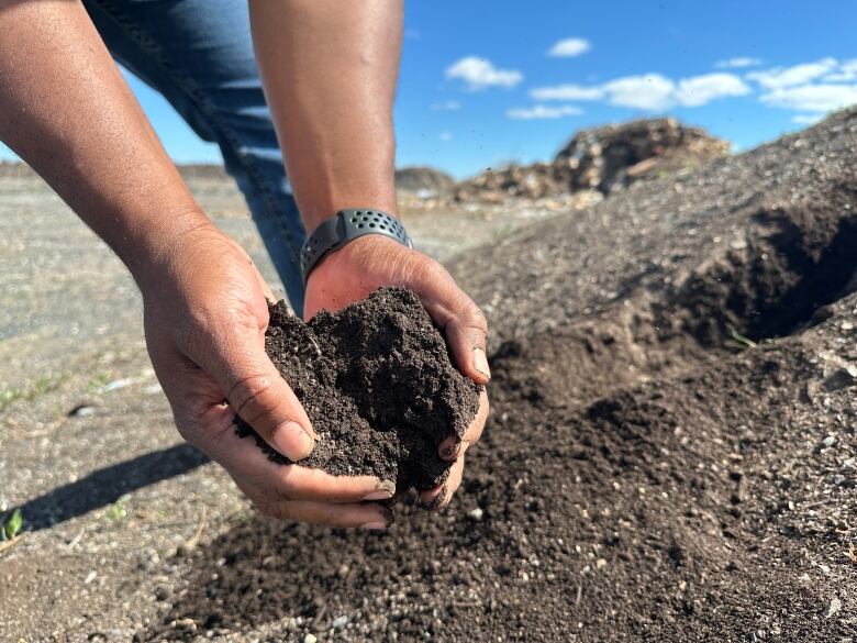 Black hands holding what appears to be soil. 