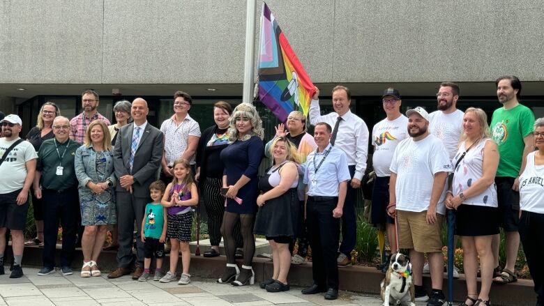 A group of people stand with the Pride Flag