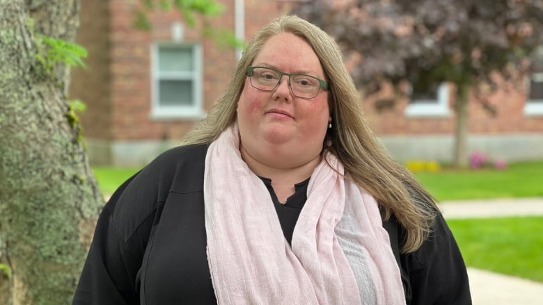 A woman in a black shirt and pink scarf is shown.