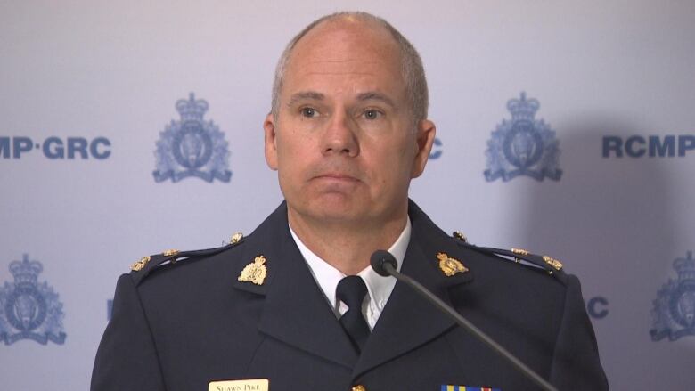 A man in a police uniform speaks at a podium.