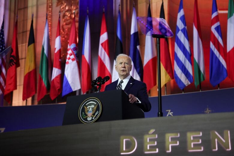 Biden with national flags behind him and the French word for 