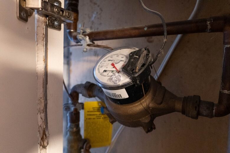 A water meter is pictured in a basement.