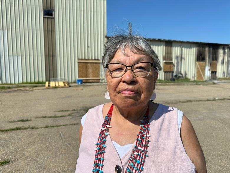 A woman stands in front of a building.