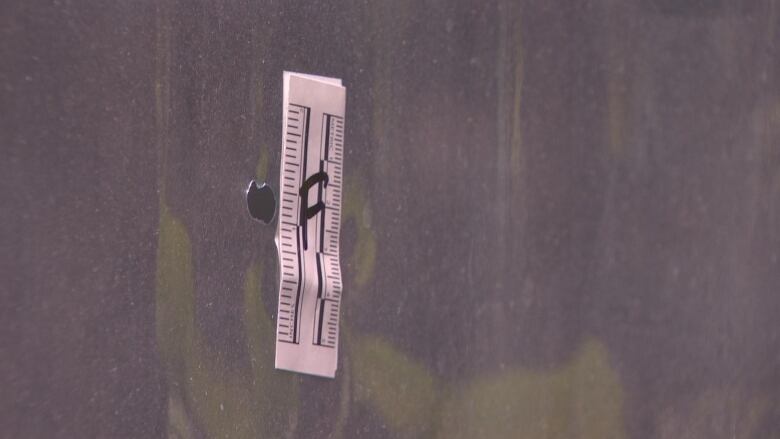 A small piercing in plastic has a ruler-like sticker next to it labelled 