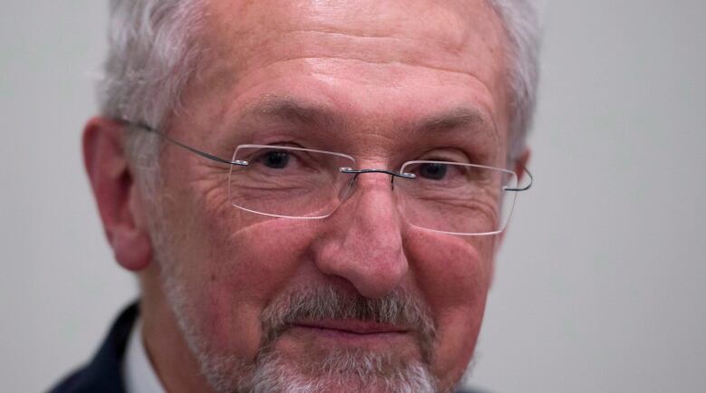 A man with glasses and a white-coloured beard smiles.