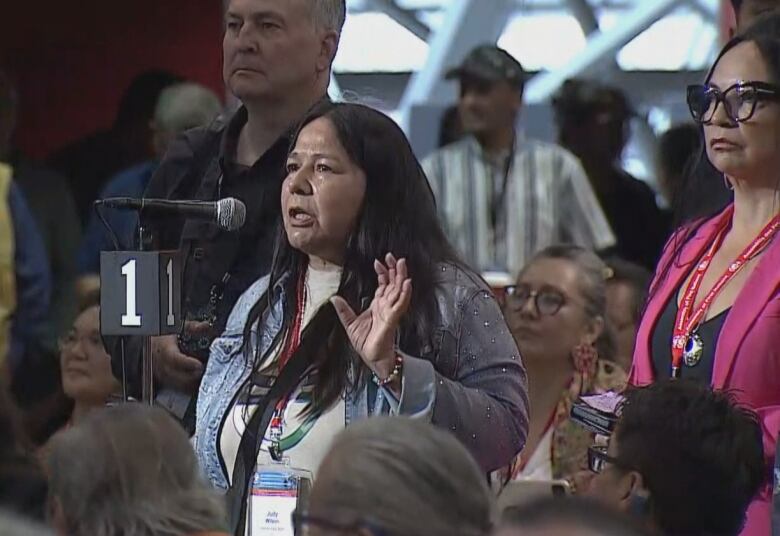 Two Indigenous women stand before a microphone in the Assembly of First Nations meeting in Montreal to ask Conservative Leader Pierre Poilievre questions after his speech.