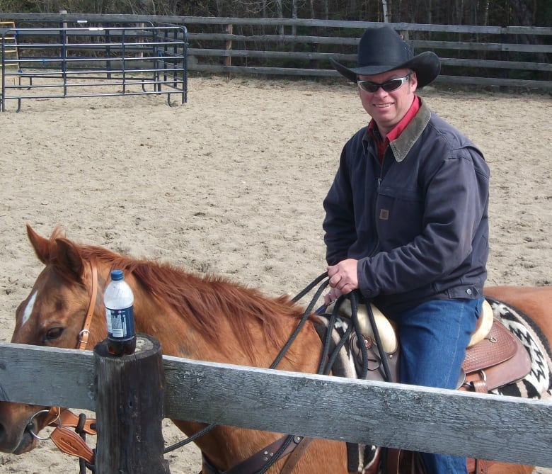 Man in black cowboy hat and coat sits on top of brown horse.