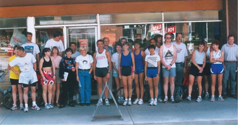 A group of roughly 20 joggers is pictured wearing running gear at a Running Room store in the 1980s.