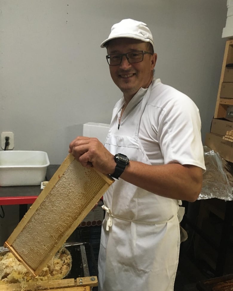 Lyndon Janiskevich harvesting honey from a honeycomb.