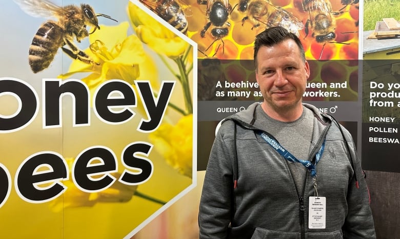 Close-up of Daniel Swan standing in front of a honeybee sign.