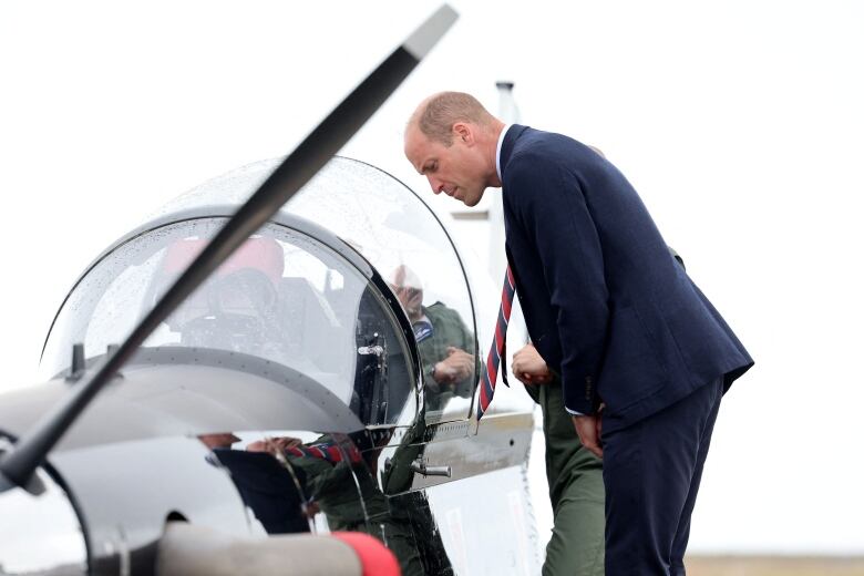 A person looking into the cockpit of a military aircraft.