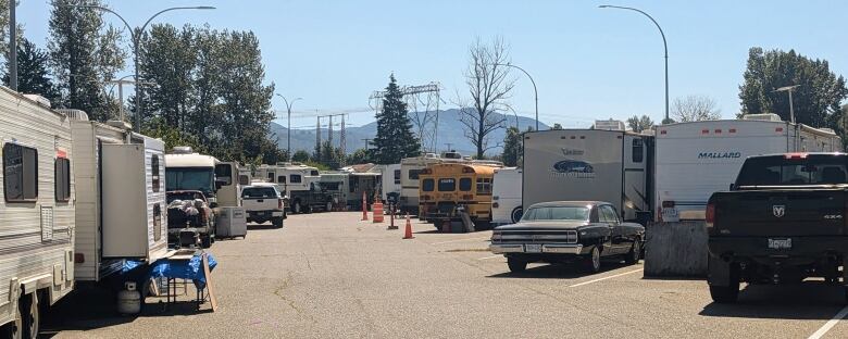 Campers, trailers, motor homes, a school bus and vehicles are all parked with a lane between them.