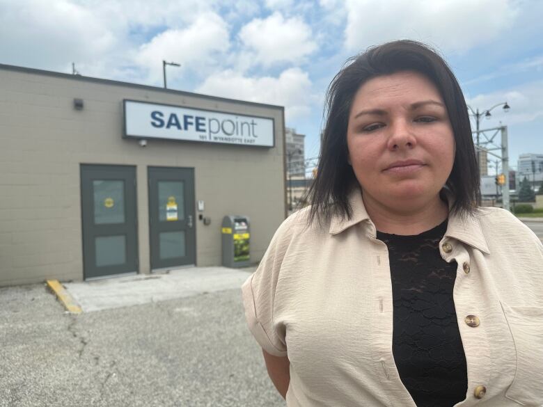 A woman stands in front of a building with a sign that reads, 'SafePoint.'