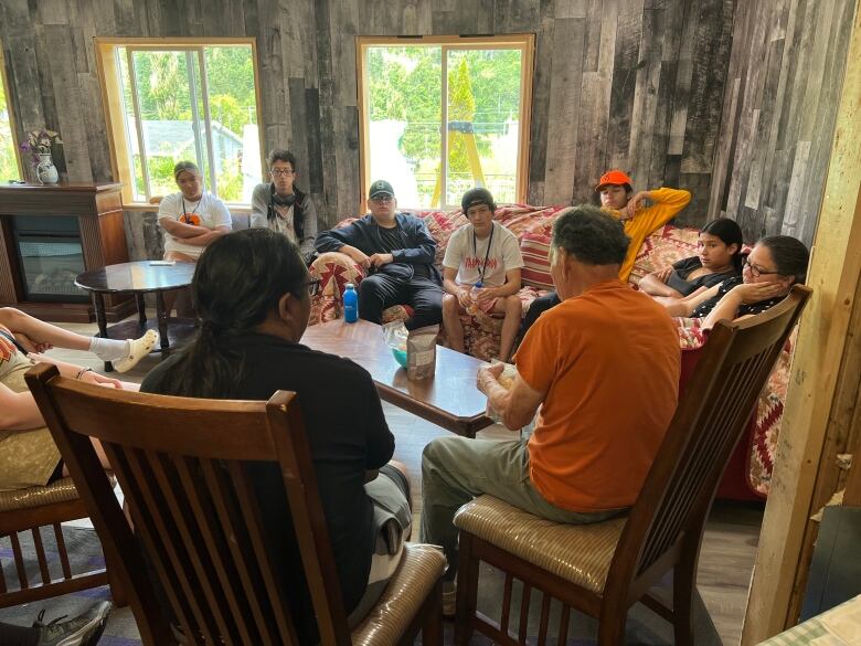 Two adults and several students are shown in a living room. 