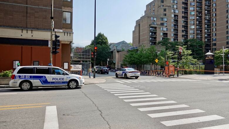 Police cars parked near an intersection with police tape. 