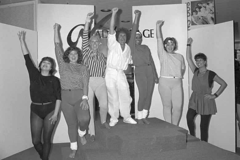 People standing on steps raise their fists as they pose for a photo.