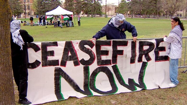 People holding a banner  that says 'Ceasefire now.'