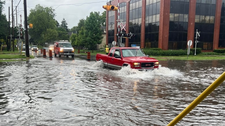 Red truck driving into a flooded intersection