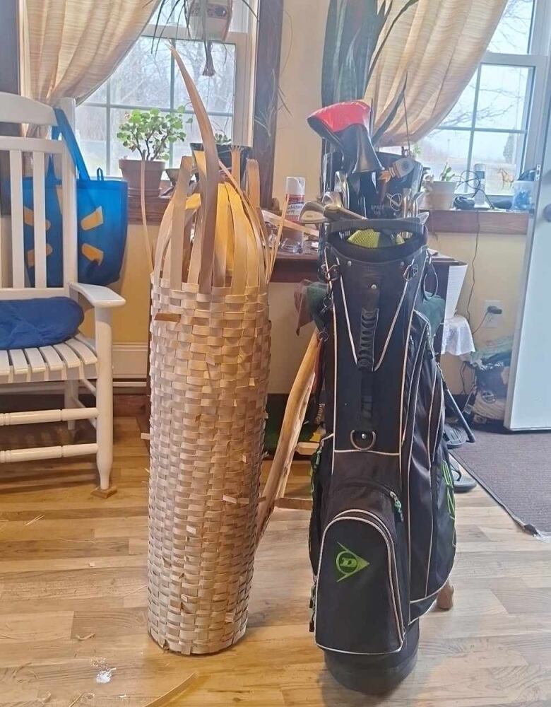 A golf bag standing next to a tall women basket.