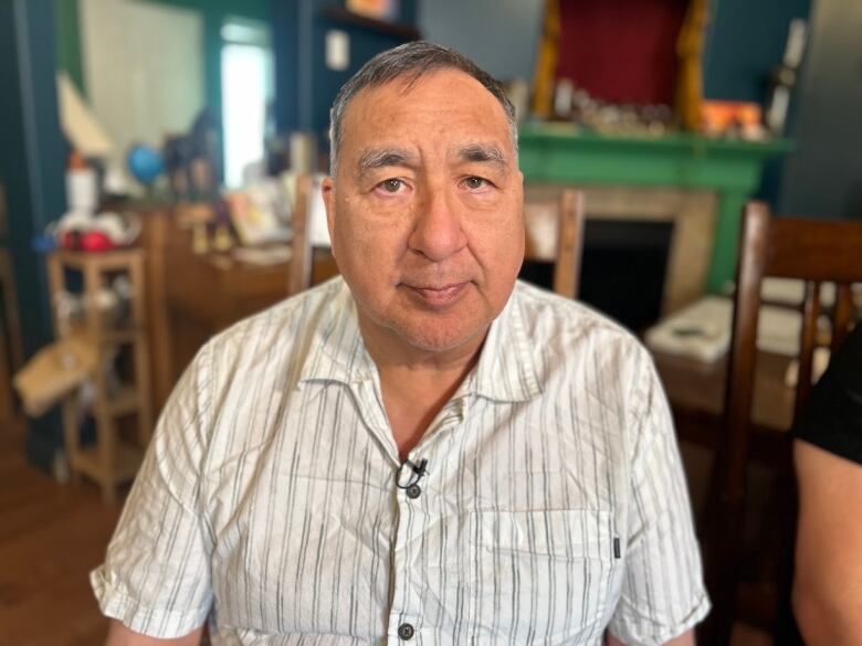 Man in striped shirt sits in house.