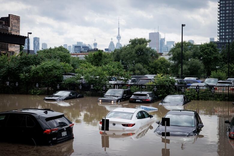 Onlookers take in the spectacle of flooded and abandoned vehicles on the Don Valley Parkway after a major rain squall caused the Don River to burst its banks on July 16, 2024.