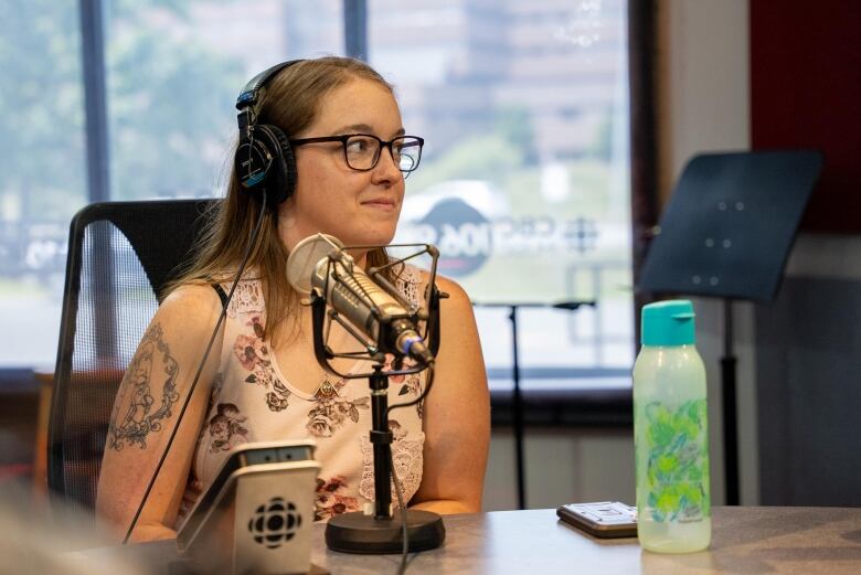 A woman with glasses sits in a radio studio