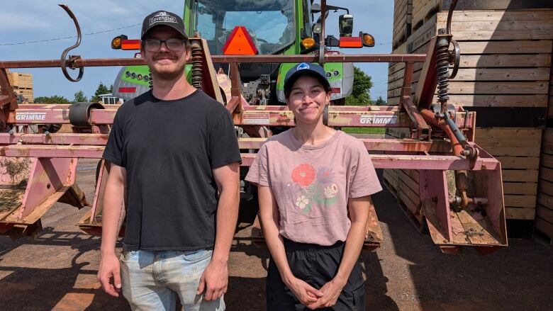 A man and a woman stand in front of a farm tractor 