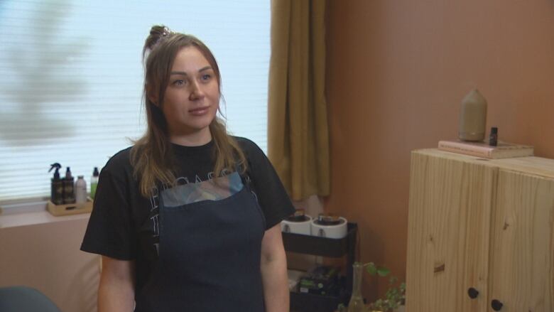 A white woman with brown hair wearing a black apron.