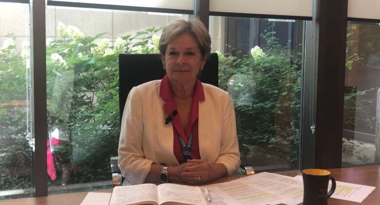 A woman sitting at a desk with her hands linked