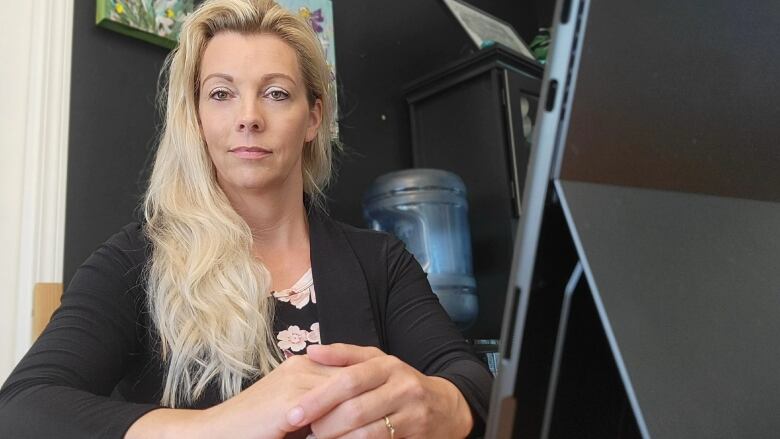 A woman with long blond hair looks into the camera lens.