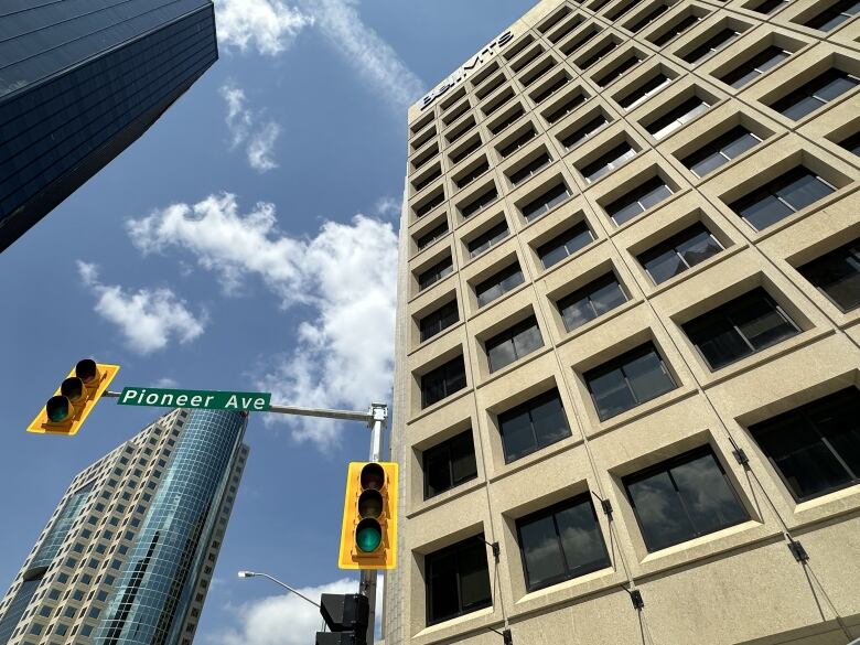 A building stands in front of traffic light, in the distance other two buildings rise.