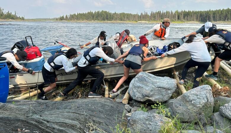 A group of youth pushing a boat up a hill