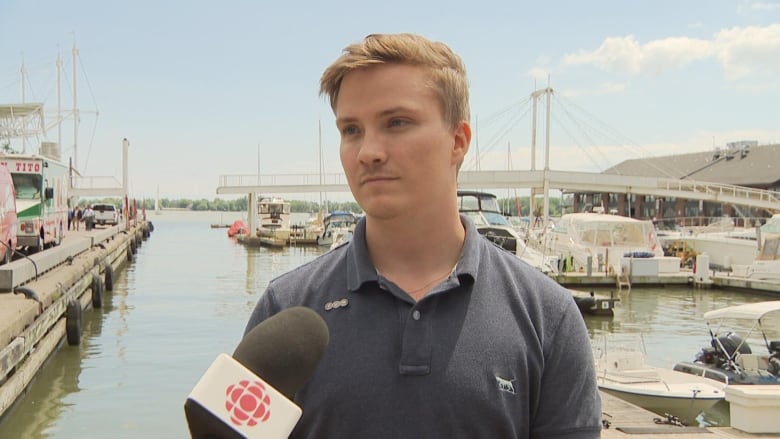 Photograph of a man speaking into a microphone in front of a bay