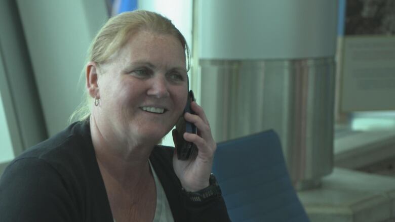 A smiling woman speaks into a cellphone.