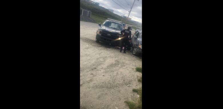 Police huddle over a woman on the ground.