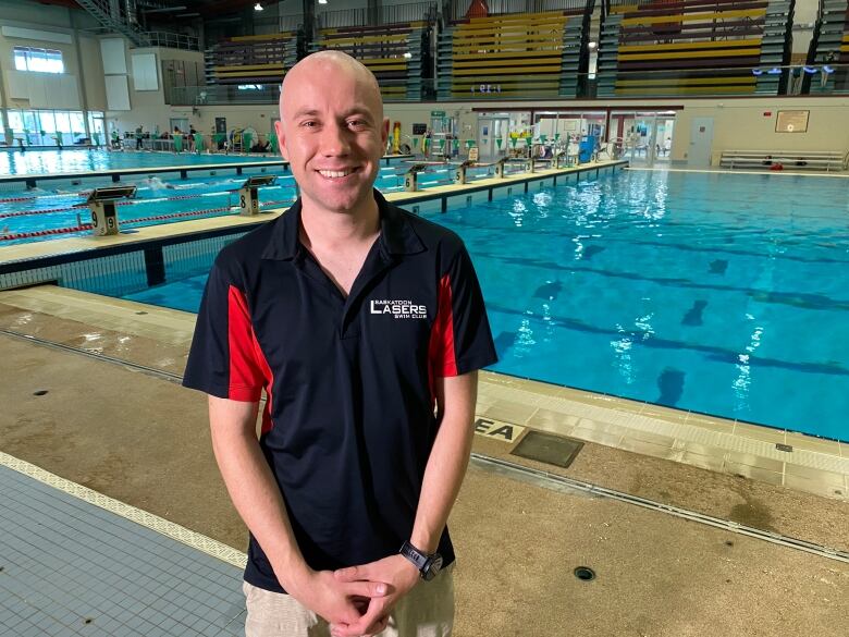 A man in a black shirt stands in front of a pool. 