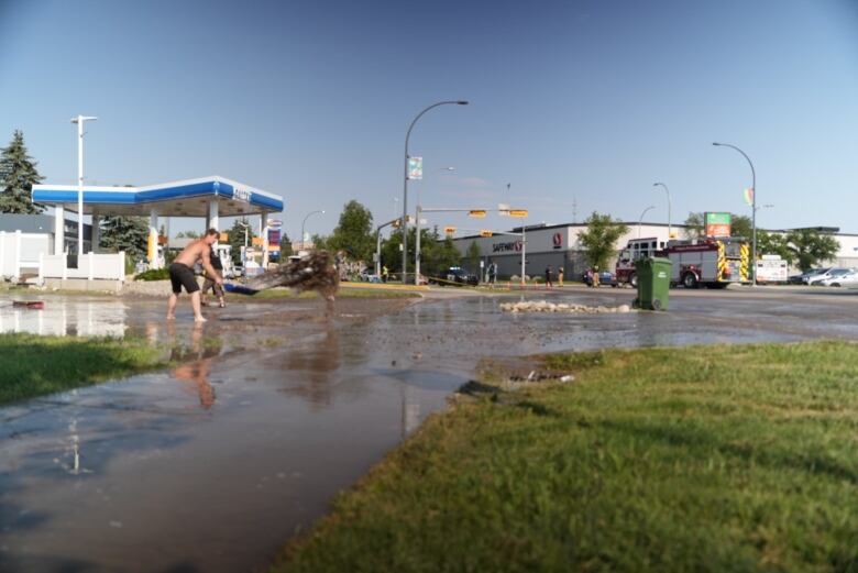 a man shovels dirty water out of a parking lot.